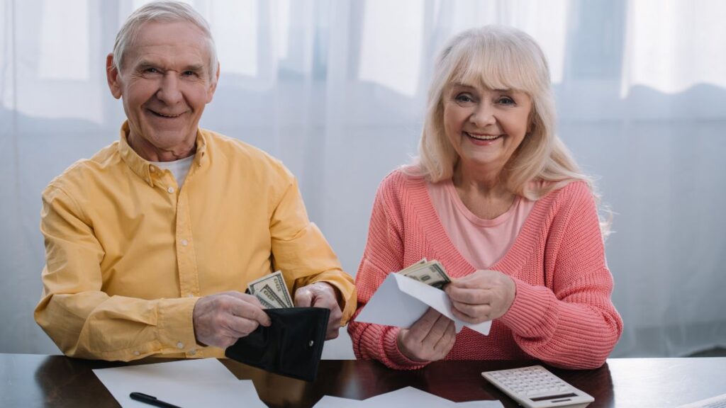 two seniors holding money in their living room