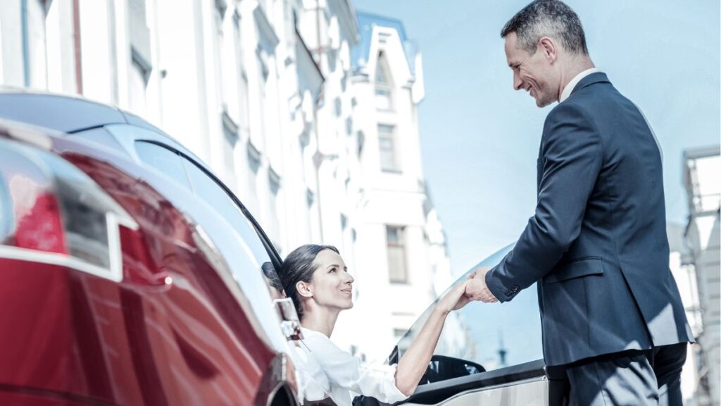 A man helping a woman come out of the car