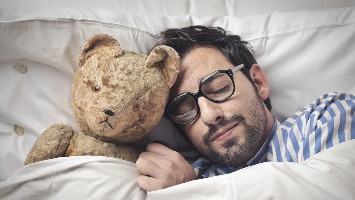 Man holding a teddy in bed