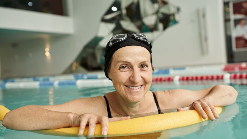 Middle aged woman swimming with a pool noodle