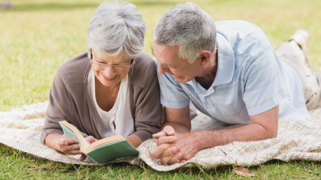 older couple reading on a blanket outside