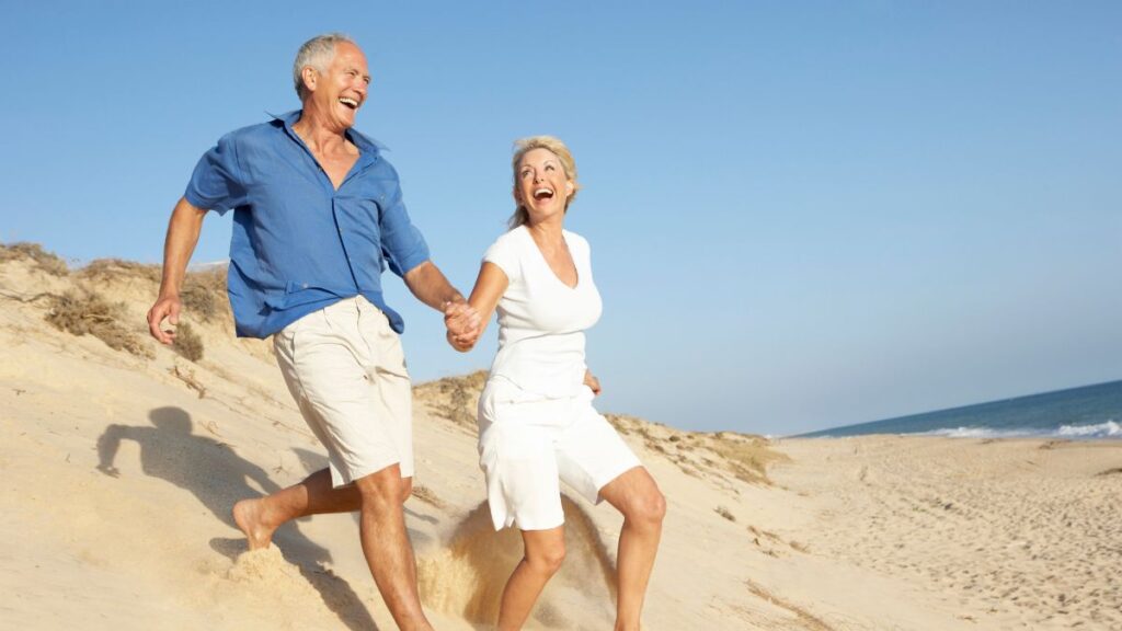 older couple running happily on the beach