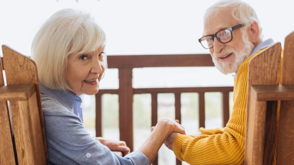 older couple sitting and holding hands happily