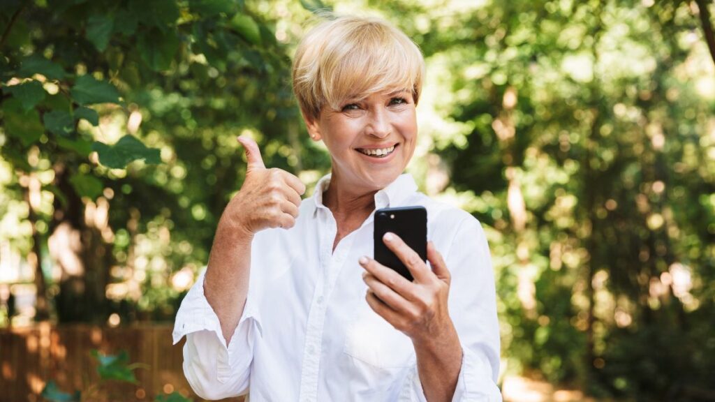 older lady looking at phone with thumb up