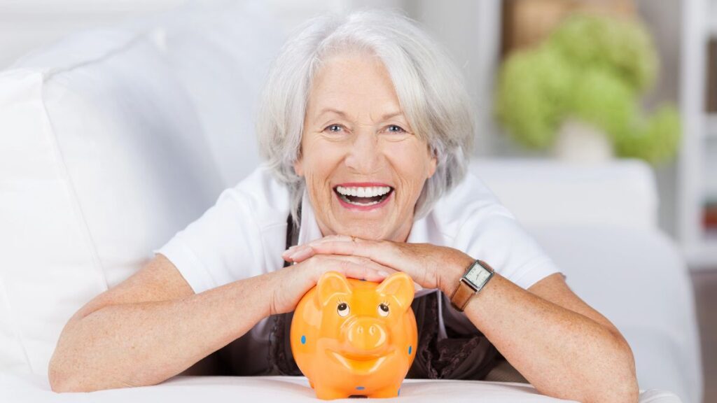 older woman smiling wih piggy bank