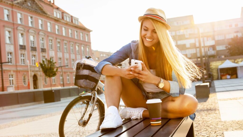 trendy woman sitting on a bench on her phone