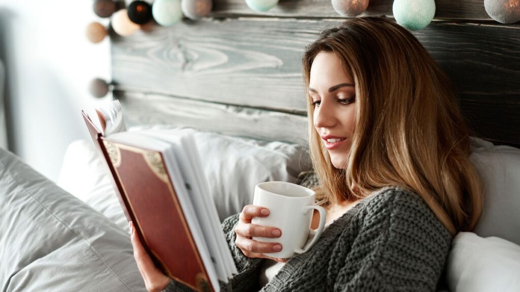 woman in bed reading with coffee