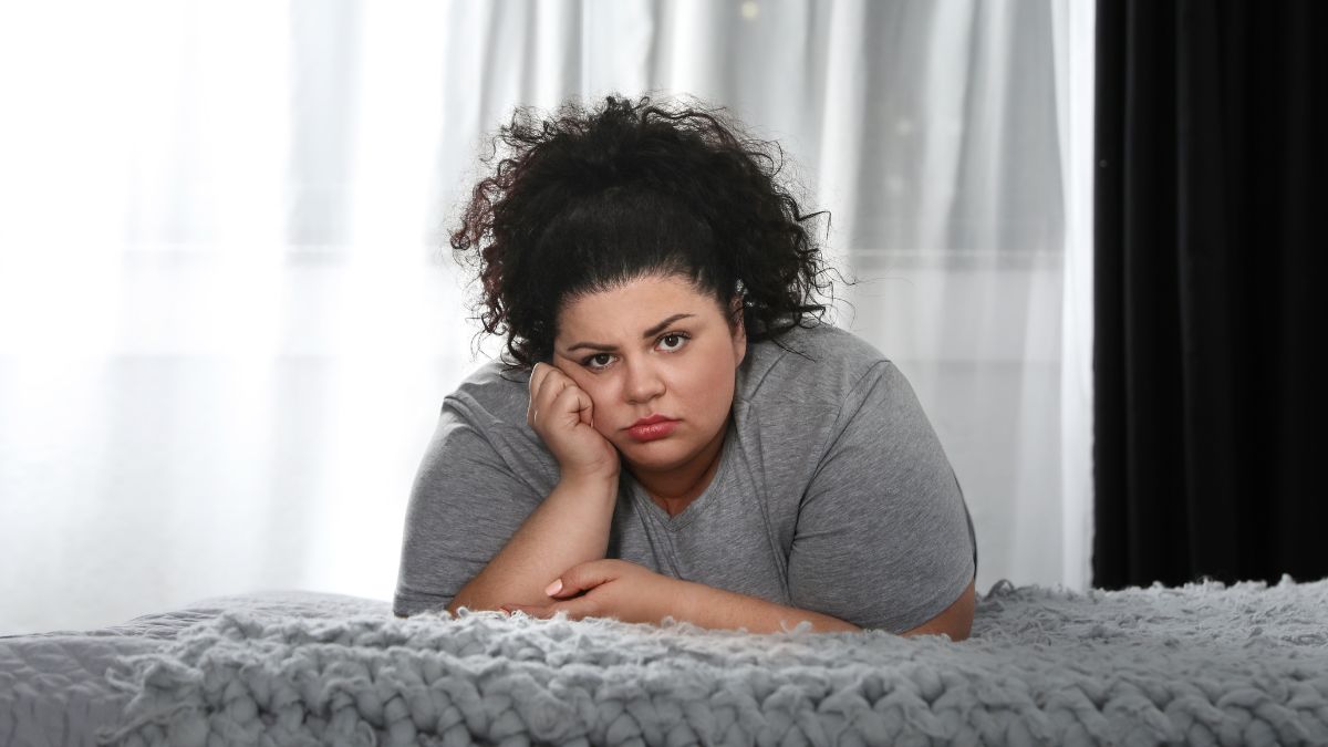 woman sad leaning over her bed