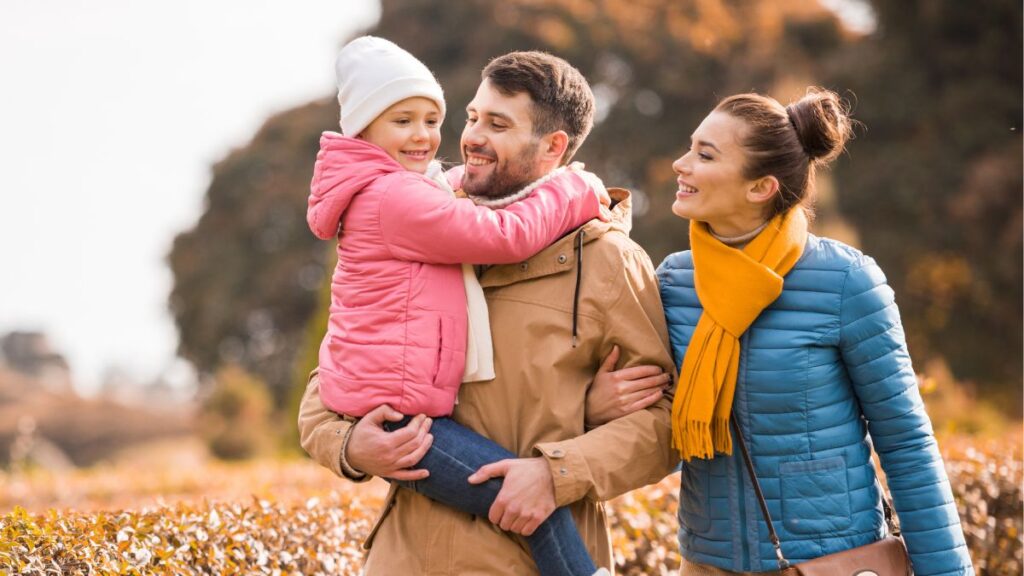 Happy family outside in a field, husband holding daughter