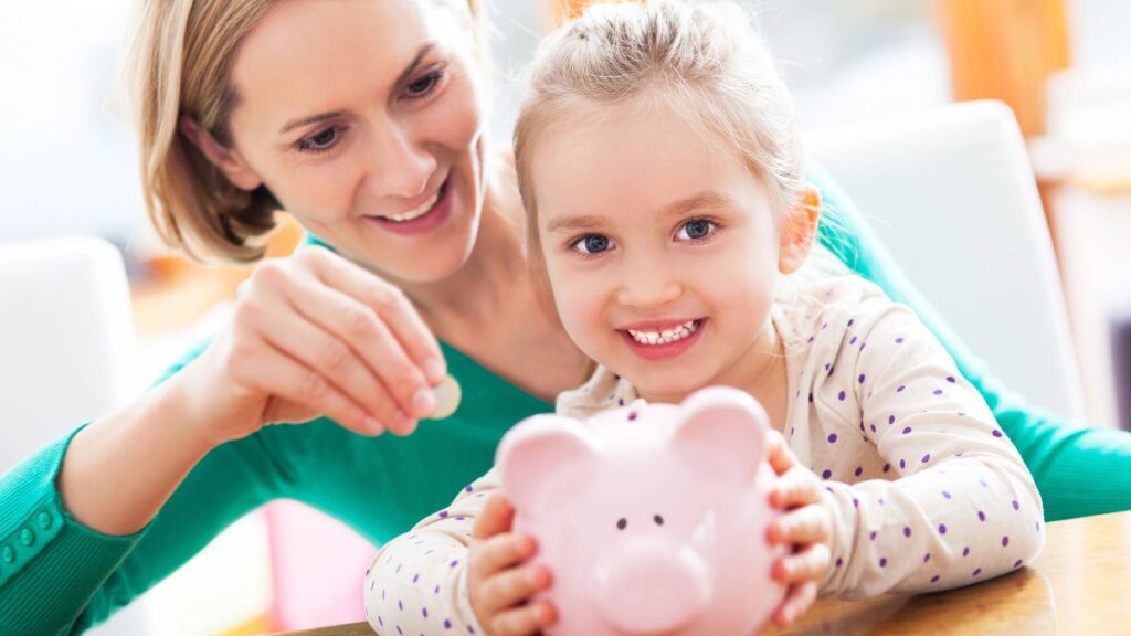 Woman and little girl adding coins to a piggy bank