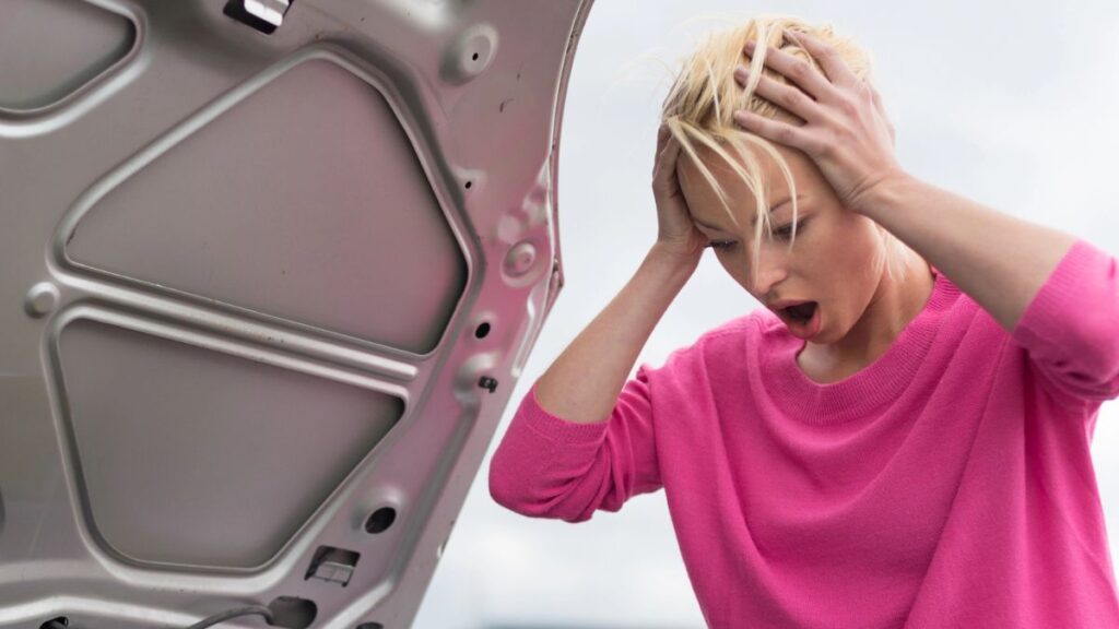 Woman shocked looking under the hood of her car