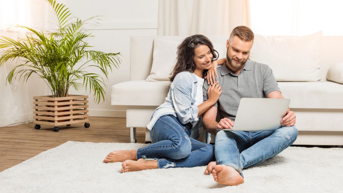 couple sitting on the floor in the living room looking at computer