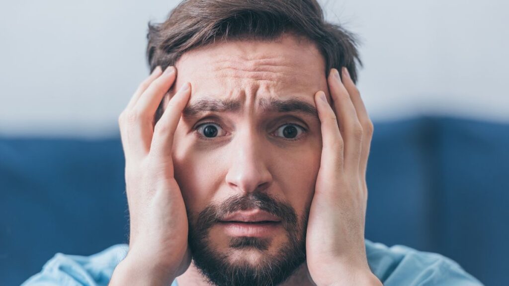 man holding his face looking worried