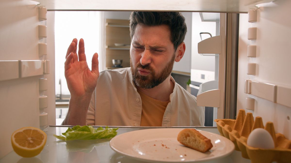 man smelling something bad in fridge