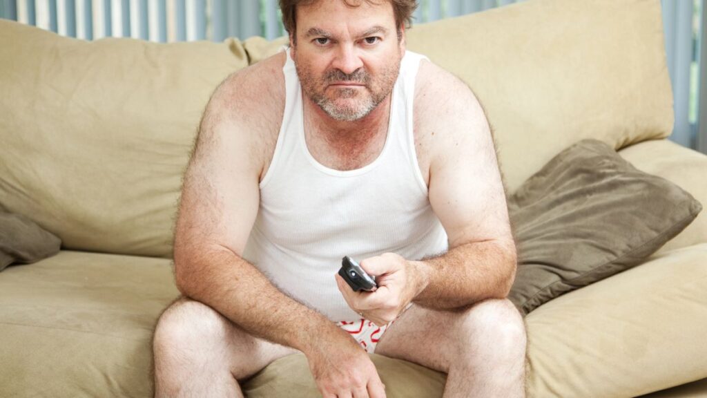 man watching tv looking grumpy in sleep clothes