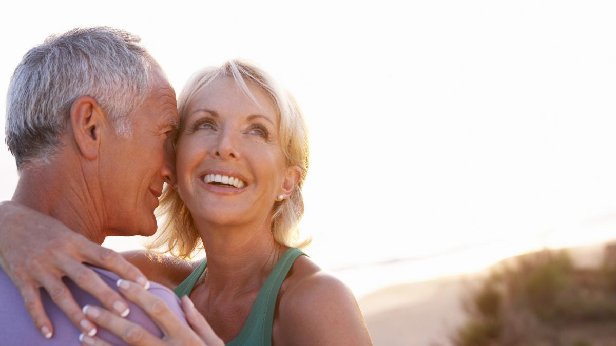 middle aged couple hugging at the beach.