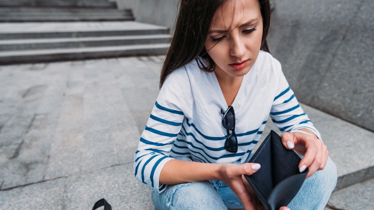 upset woman looking at empty wallet