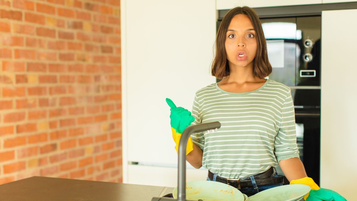 woman cleaning dishes looking surprised