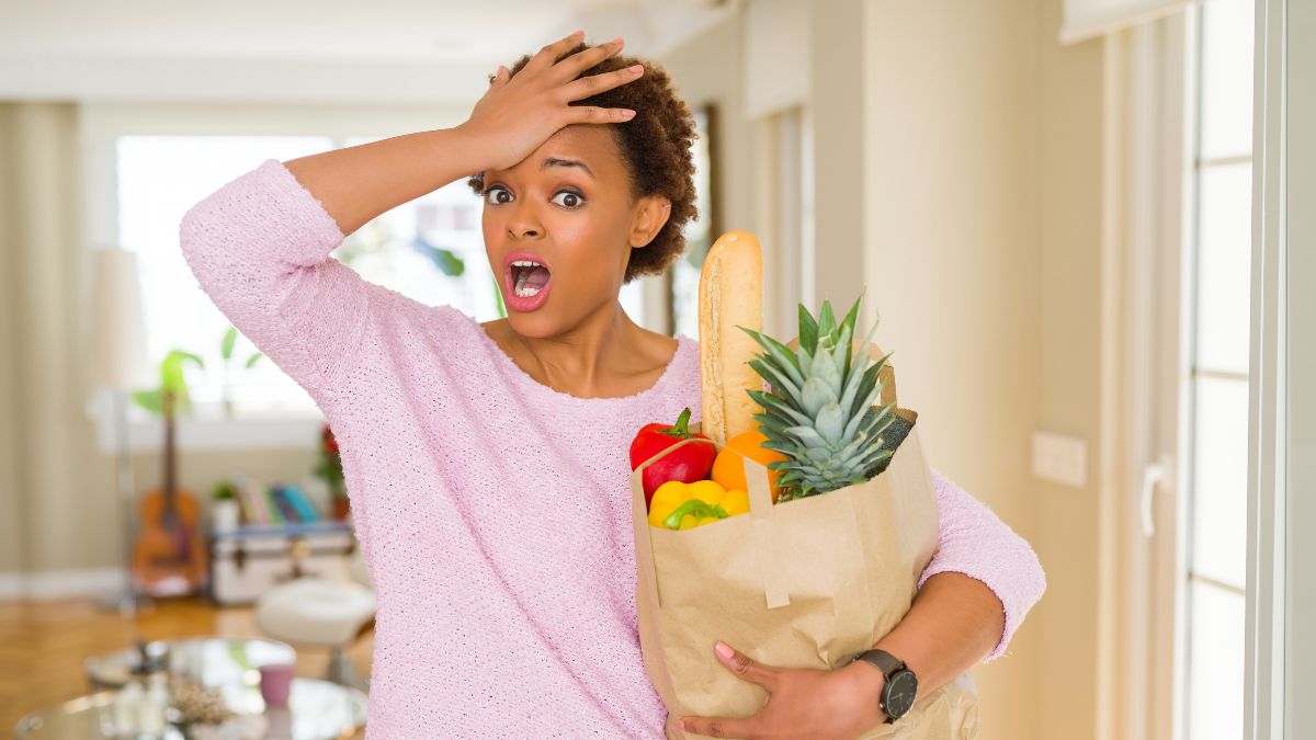 woman hand on her head with a bag of groceries looking shocked