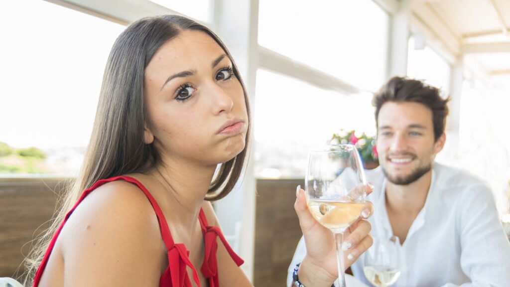 woman holding a wine glass on a bad date, looking annoyed