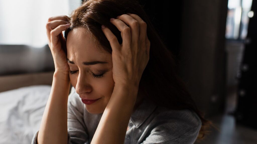 woman holding her head looking sad