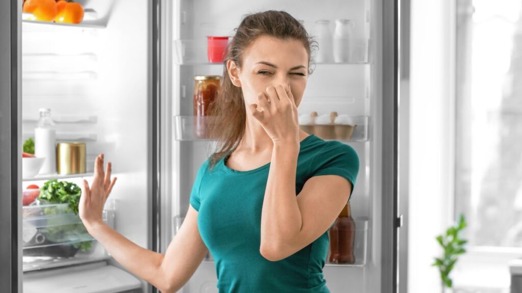 woman holding her nose outside the fridge