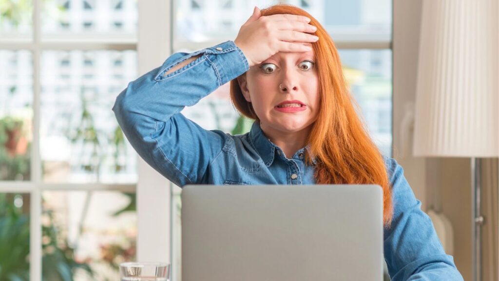 woman looking concerned at computer hand on head