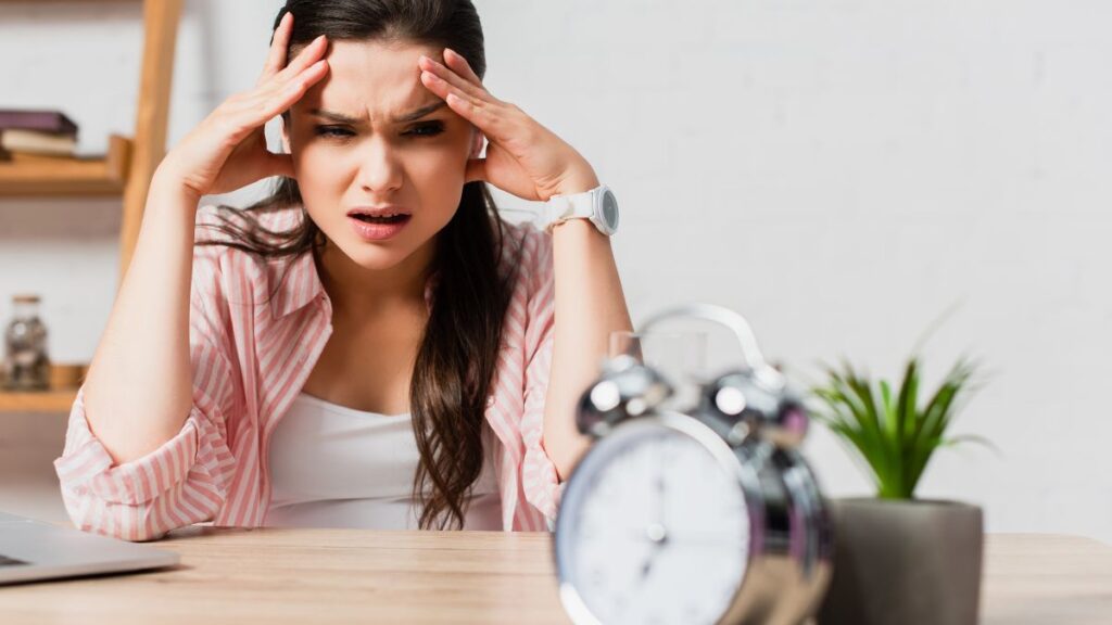 woman looking stressed at an old alarm clock