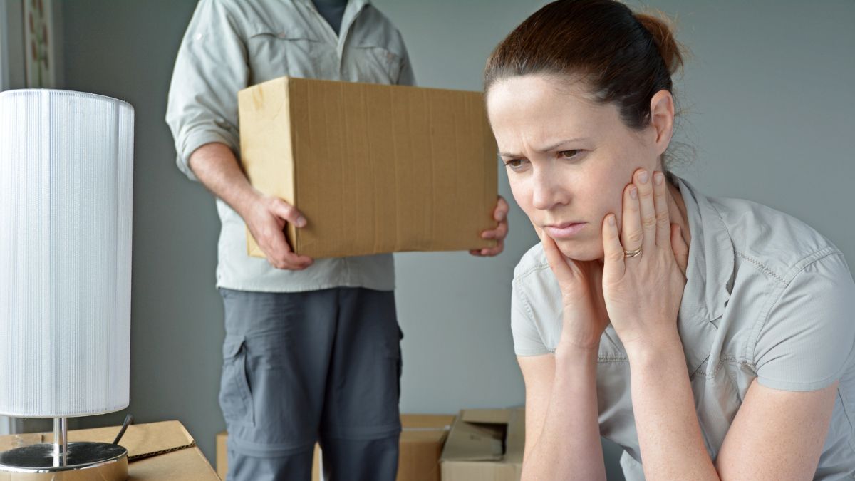 woman looking upset behind her is boxes and a man holding a moving box