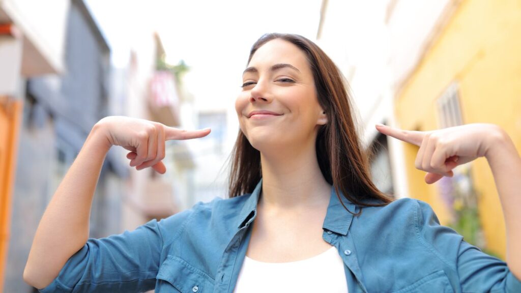 woman smiling pointing at herself