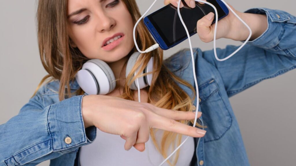 woman wanting to cut the cord off her headphones from her phone