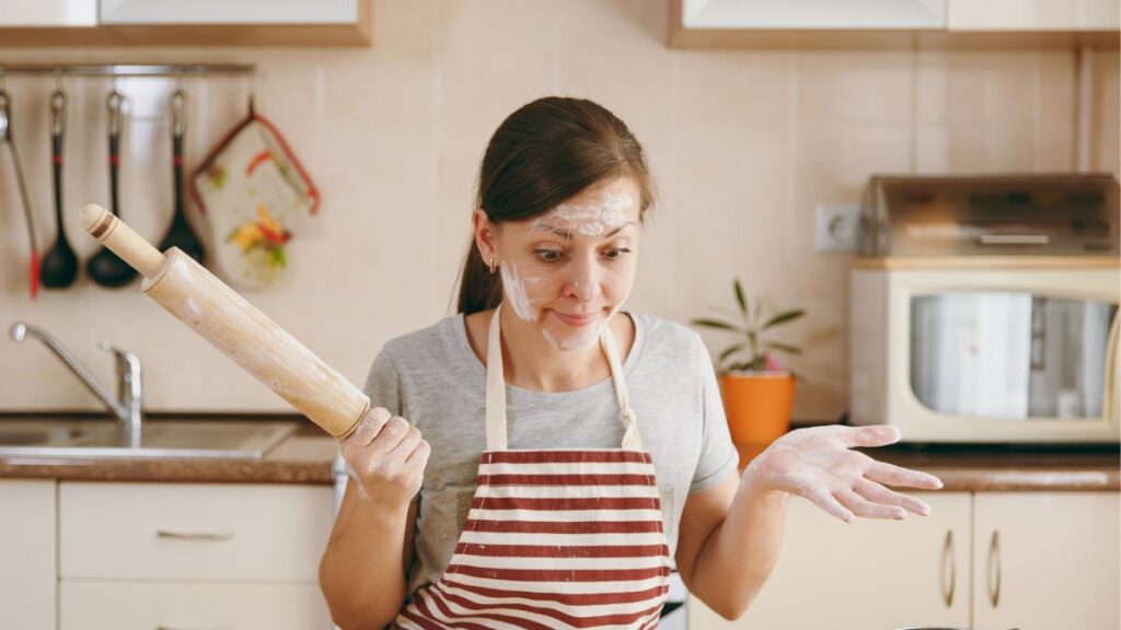 woman with flour on her face, holding a rolling pin