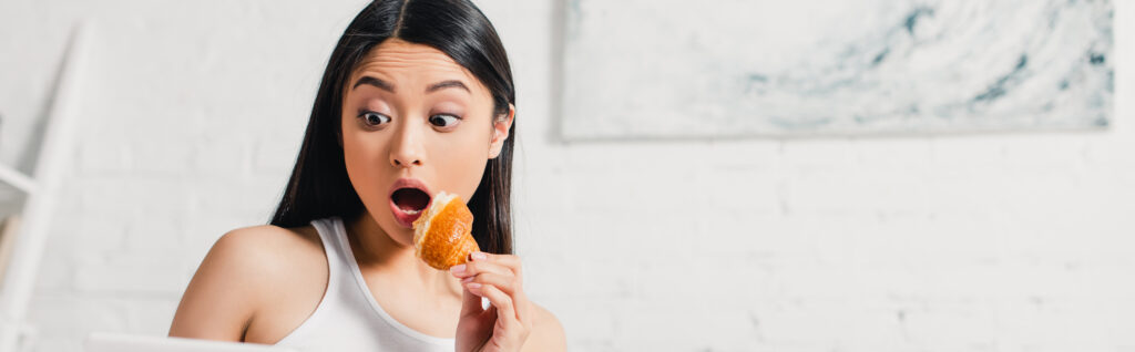 Woman eating a pastry looking surprised