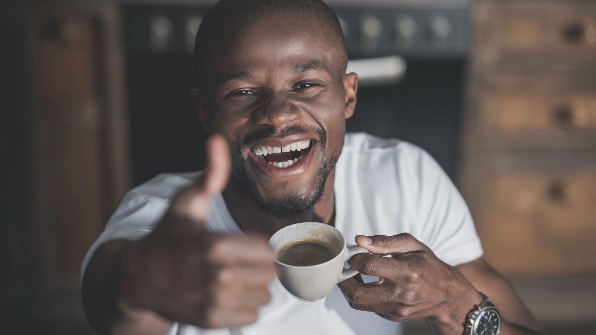 Happy man drinking coffee giving a thumbs up