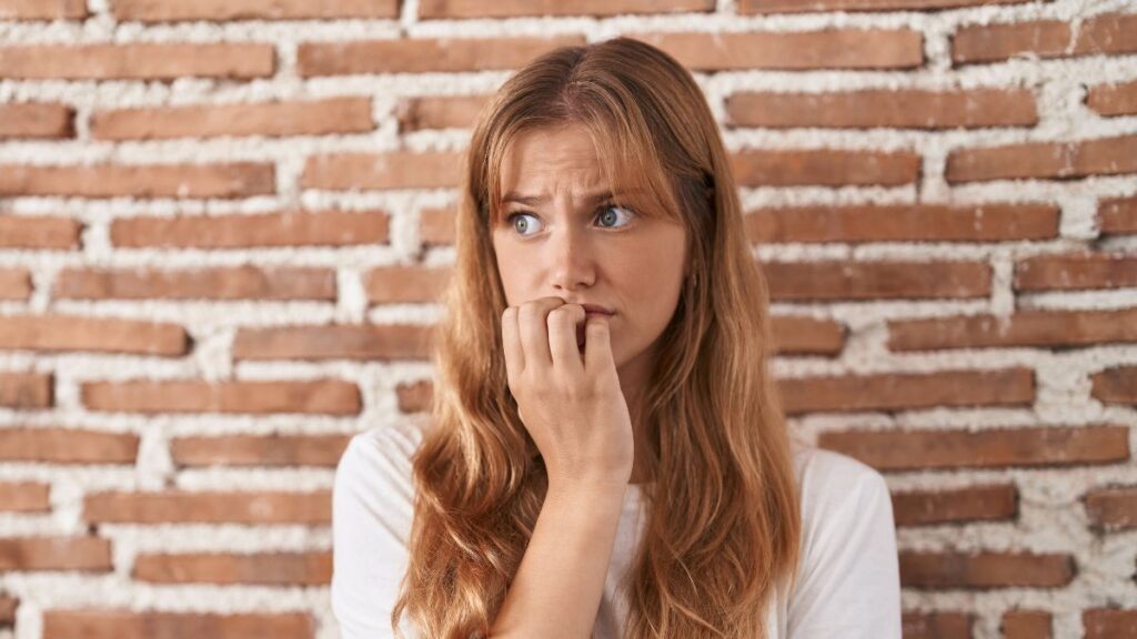 Woman looking insecure infront of a brick wall