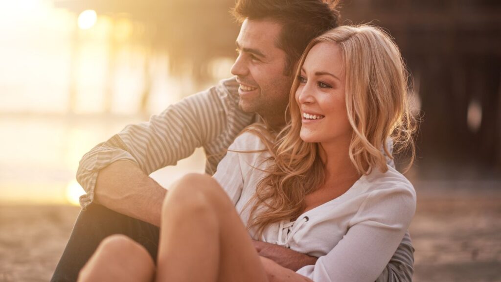 Young couple sitting on the beach looking at the beach