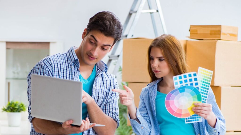 a couple looking at a laptop holding paint samples