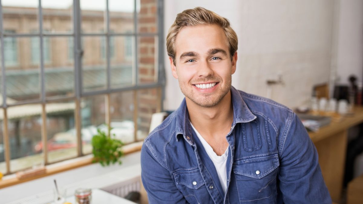 blond man with jean shirt smiling in office