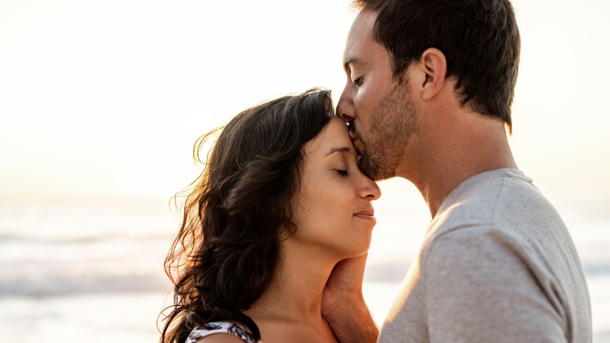 couple on the beach man kissing womans head