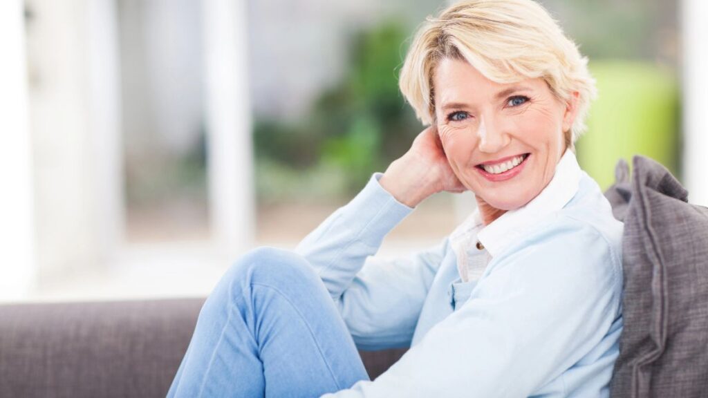 happy older woman sitting on the couch knees up