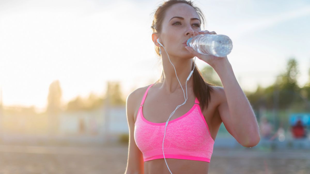 healthy woman drinking water on the beach