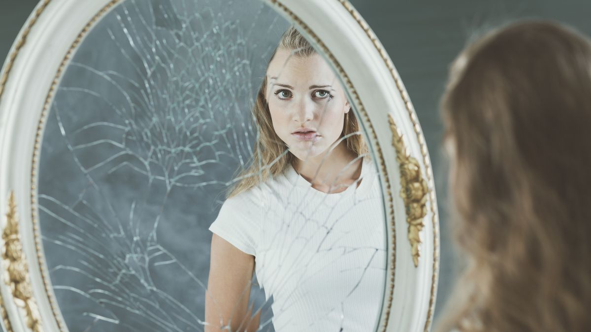 insecure woman looking at broken mirror