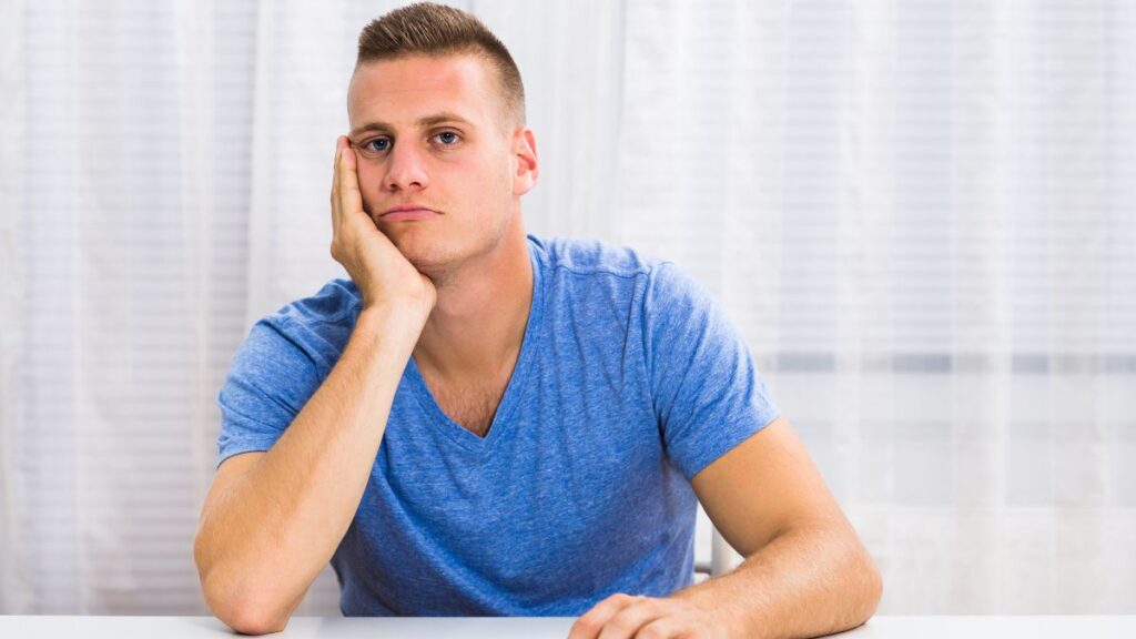 man in blue looking irritated at the table