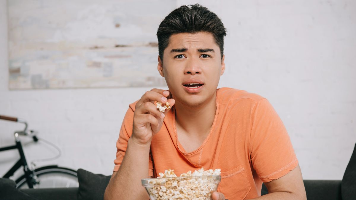 man looking shocked eating popcorn