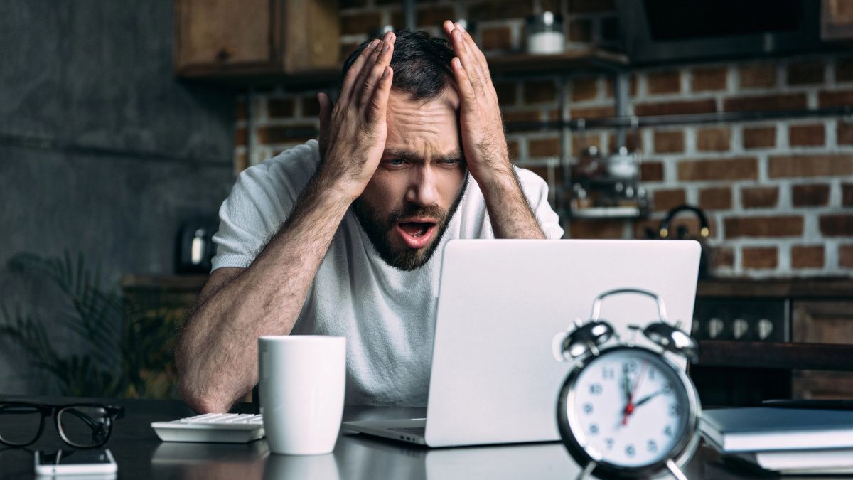 man looking shocked with hands on face at computer