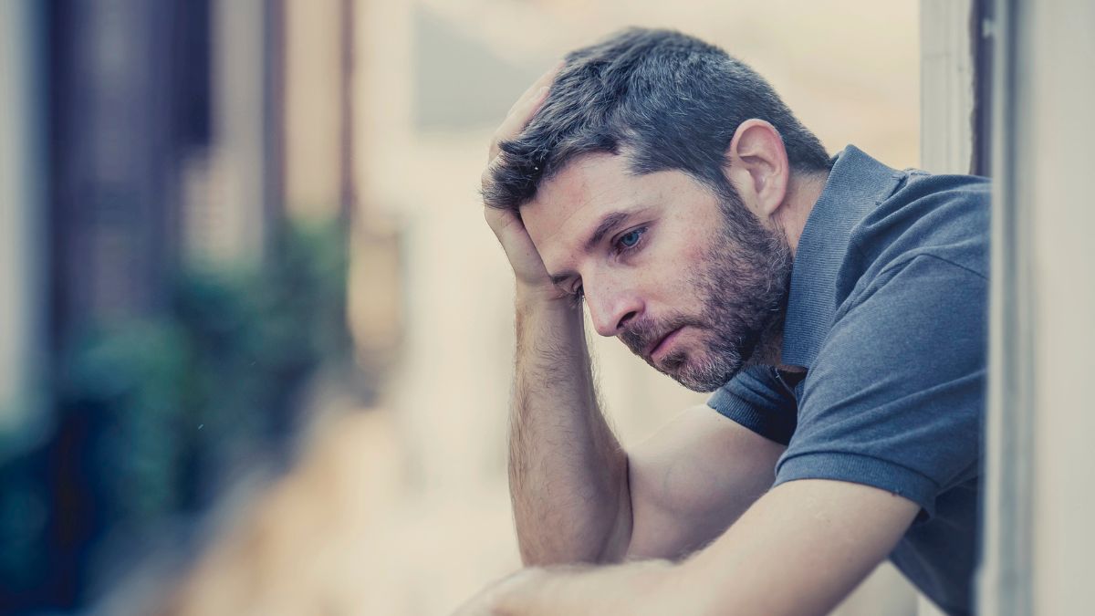 man looking stressed and depressed on a balcony