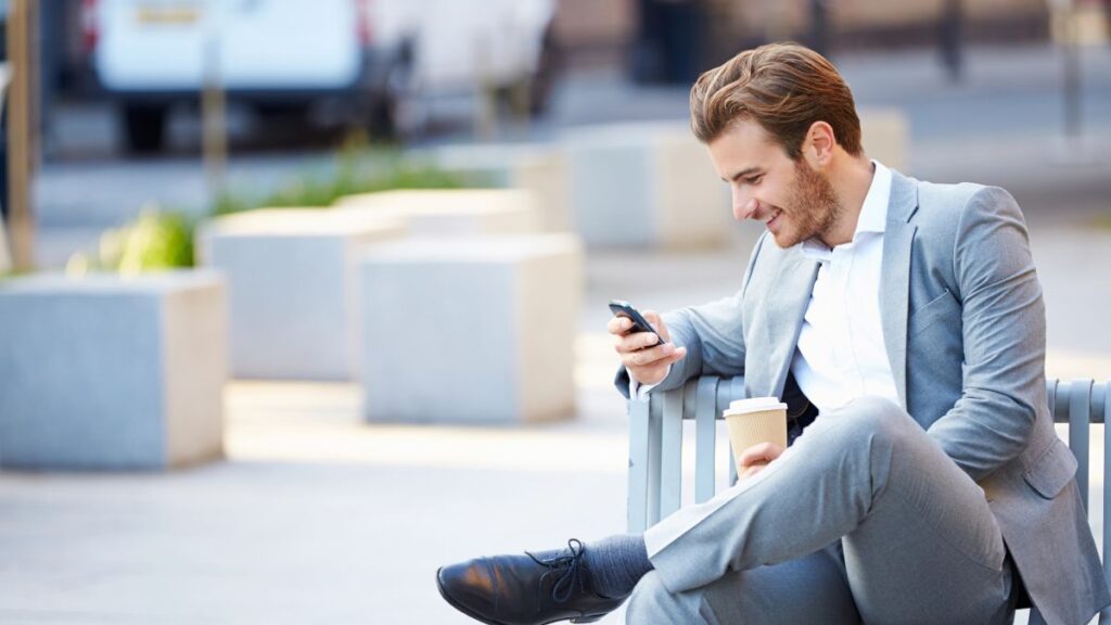 man on his phone sitting on a bench