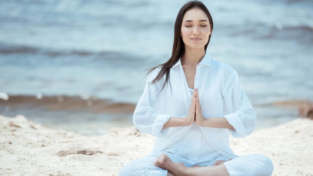 woman doing meditation on beach