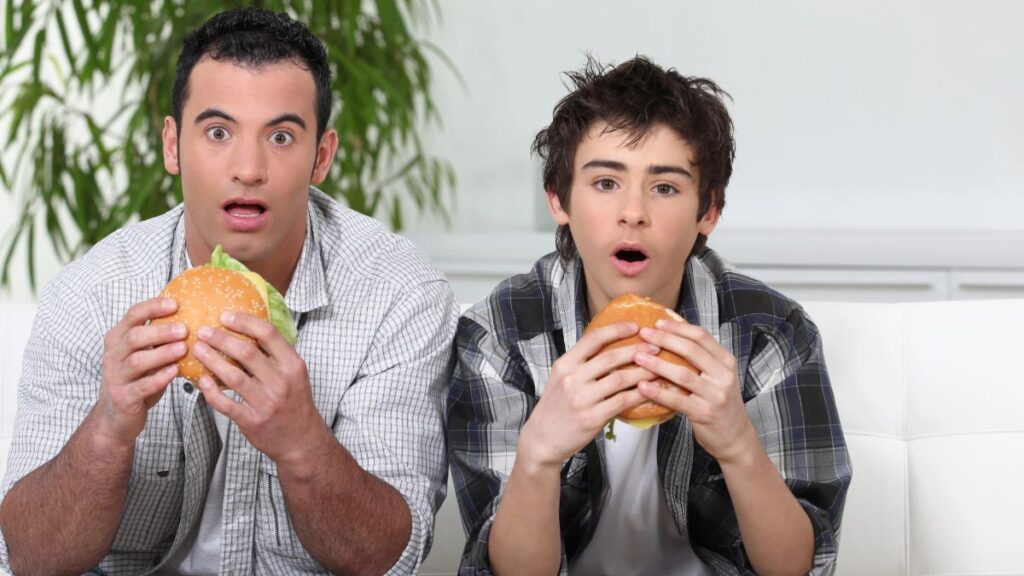 son and dad eating burgers looking shocked