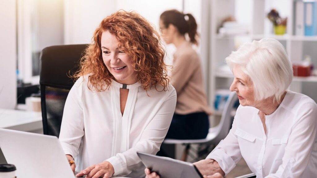 two women, one older with grey hair working at desk